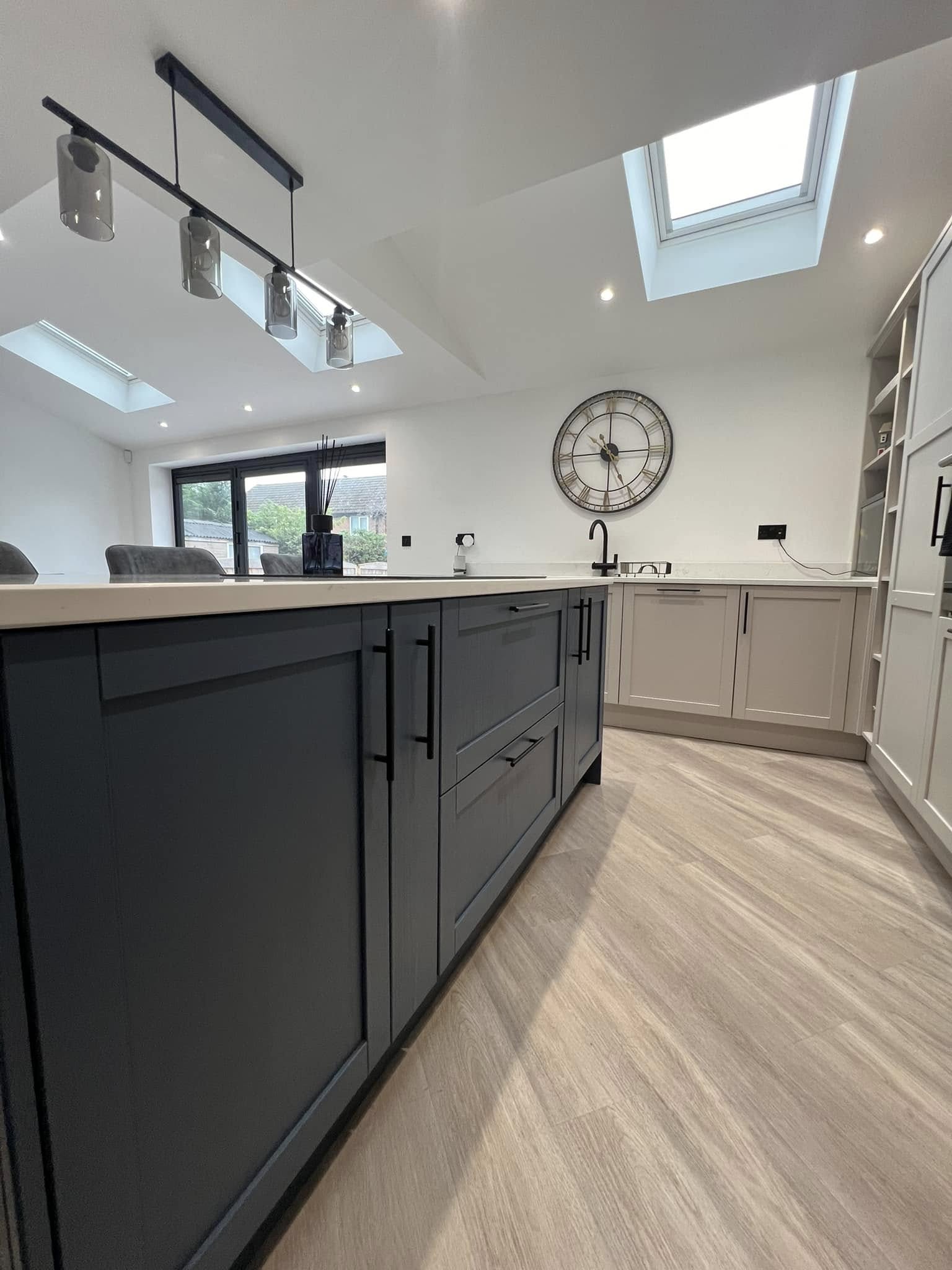 Open plan kitchen extension with dark island, pendant lights and LED downlights installed by Matrix FSE